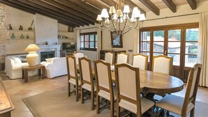 Zona pranzo con tavolo e sedie in legno, un lampadario e un camino.