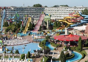 En vandpark med flere vandrutsjebaner og pools, omgivet af liggearealer og parasoller.