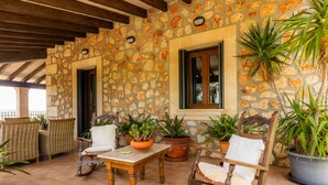 A stone-walled patio with wicker furniture, potted plants, and a wooden table. - Holiday Home 'Can Corem De Son Moix' with Mountain Views, Wi-Fi and Air Conditioning (Manacor)