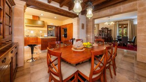 A spacious dining area with a wooden table and chairs, a kitchen in the background, and a chandelier. - Holiday Home 'Can Corem De Son Moix' with Mountain Views, Wi-Fi and Air Conditioning (Manacor)