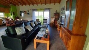 Una sala de estar con un sofá negro, una mesa de centro de madera y un televisor.