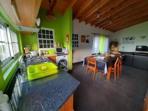 A kitchen with a washing machine, a dining area with a table and chairs, and a window with blinds.