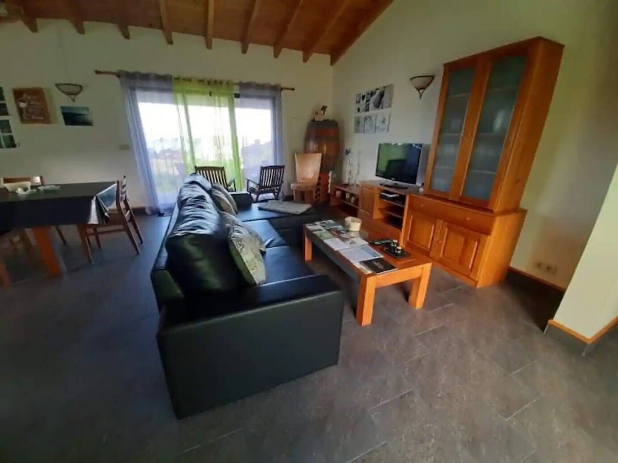 Ein Wohnzimmer mit einer Couch, einem Esstisch, einem Fernseher und einem Schrank.
