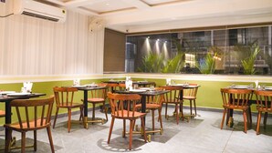 A restaurant with multiple tables and chairs, air conditioning units, and a view of greenery through large windows. - Ariena by ABA Hotels (Morjim)