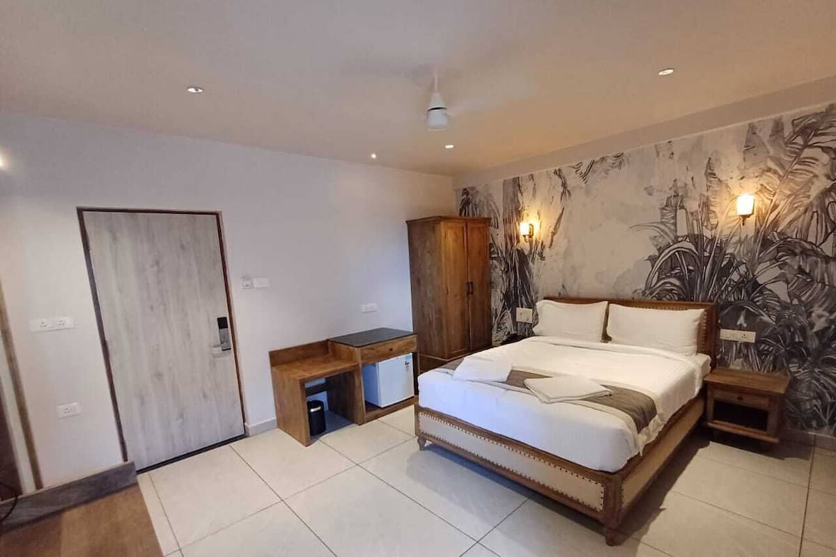A modern bedroom with a large bed, wooden nightstands, a wardrobe, and a small desk.