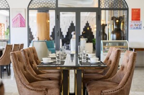 Comedor con una mesa larga dispuesta para cuatro personas, rodeada de sillas tapizadas con diseño capitonado.