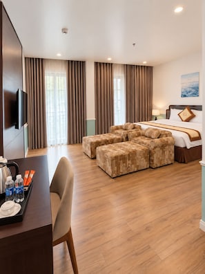 Habitación de hotel con cama, zona de estar, escritorio con hervidor y televisión.