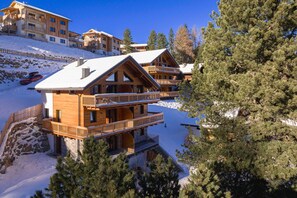 Una cabaña de madera con varios balcones y un terreno cubierto de nieve.