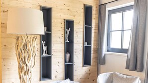 Une pièce aux murs en bois, avec un lampadaire, deux chaises et des étagères intégrées ornées d’objets décoratifs.