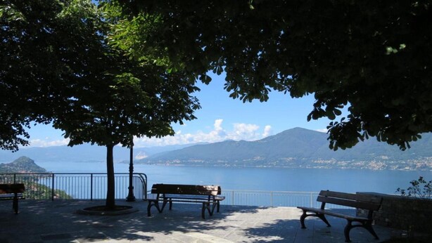 Un banco en un parque con vistas panorámicas a un cuerpo de agua y montañas.