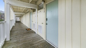 A corridor with wooden flooring, white walls, and doors numbered 313. - Gulf front condo with sunset views (Cedar Key)