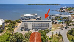 A hotel with a large building, a swimming pool, and a view of the ocean. - Gulf front condo with sunset views (Cedar Key)