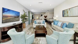 Ein modernes Wohnzimmer mit Flachbildfernseher, Couchtisch, zwei Sofas, Essbereich und einer Treppe.