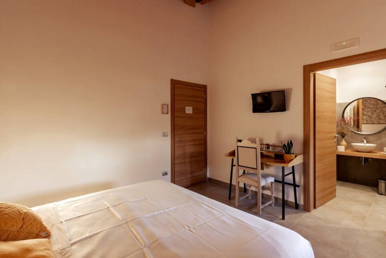 Ein Schlafzimmer mit Bett, Schreibtisch und einem Badezimmer mit Waschbecken und Spiegel.