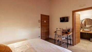 Ein Schlafzimmer mit Bett, Schreibtisch und einem Badezimmer mit Waschbecken und Spiegel.