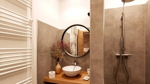 A bathroom with a round mirror, a wooden vanity, a white sink, a shower, and a towel rack. - Tenuta San Martino - Irpinia (Nusco)