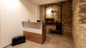 A reception desk with a wooden finish, a stone wall, and a hanging light fixture. - Tenuta San Martino - Irpinia (Nusco)