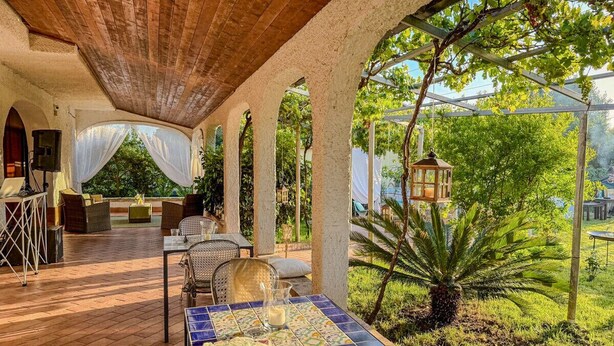 Eine Terrasse im Freien mit Holzboden, einem Tisch mit gemustertem Tischläufer und einer Laterne.