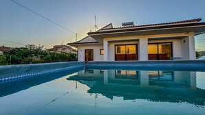 Ein modernes Haus mit Schwimmbad, großen Fenstern und einem Ziegeldach.