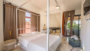 Ein Schlafzimmer mit Himmelbett, Badewanne und Fernseher.