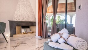 Ein Zimmer mit Kamin, einer Sitzecke mit Tisch und Blick ins Grüne.