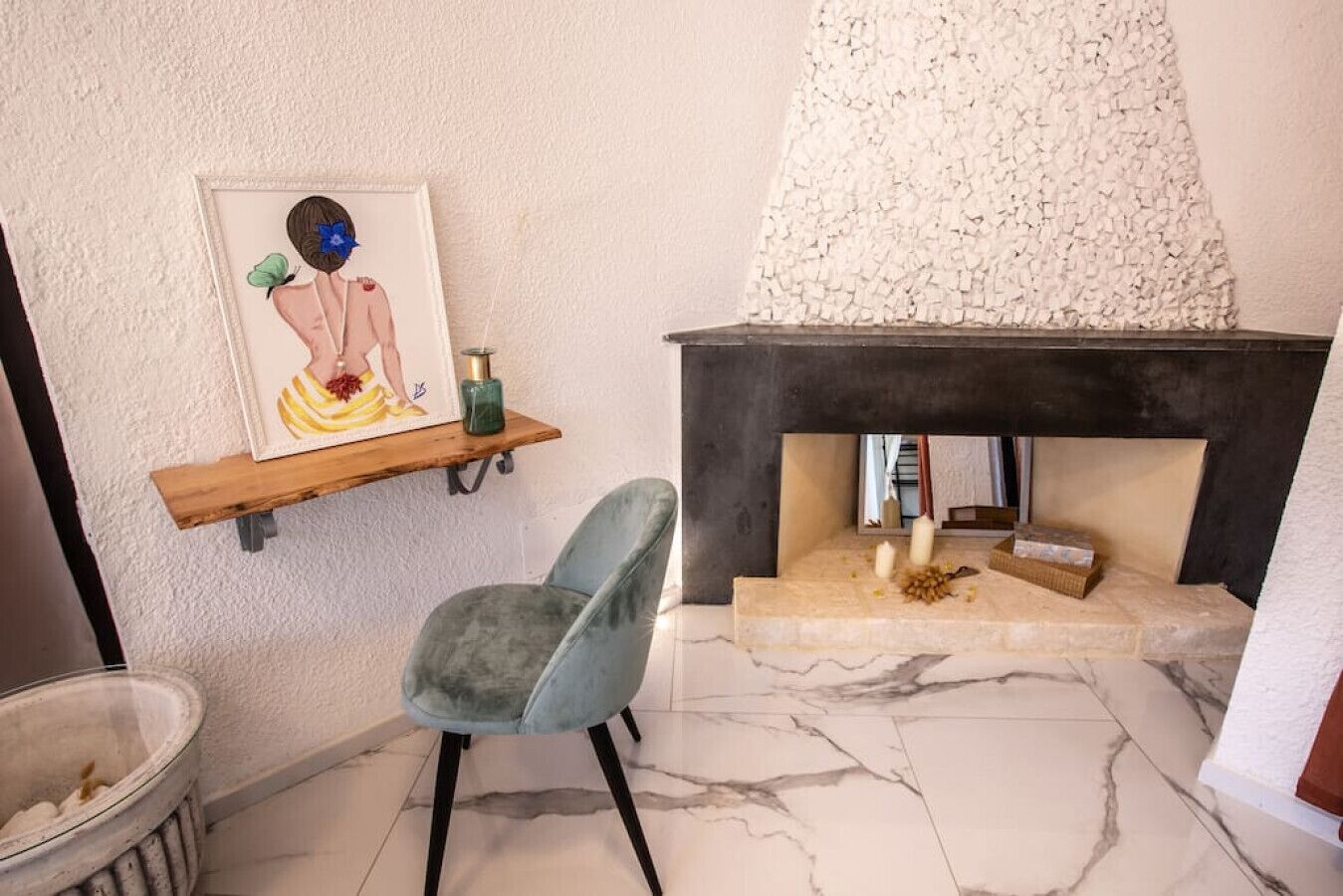 A room with a marble floor, a fireplace, a framed artwork, a blue chair, and a shelf with decorative items.