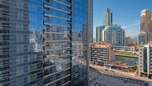 A high-rise building with a glass facade reflecting the cityscape. - Cozy 1BR with balcony sea view (Dubai)