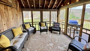 Un patio cubierto con mobiliario de mimbre, piso estampado y vistas al exterior.
