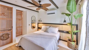 A modern bedroom with a bed, ceiling fan, air conditioning unit, and a large potted plant. - K-Log Studios  (Kas)