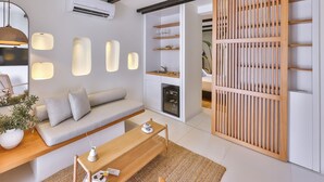 A modern living room with a sofa, coffee table, and a wooden partition with shelves. - K-Log Studios  (Kas)