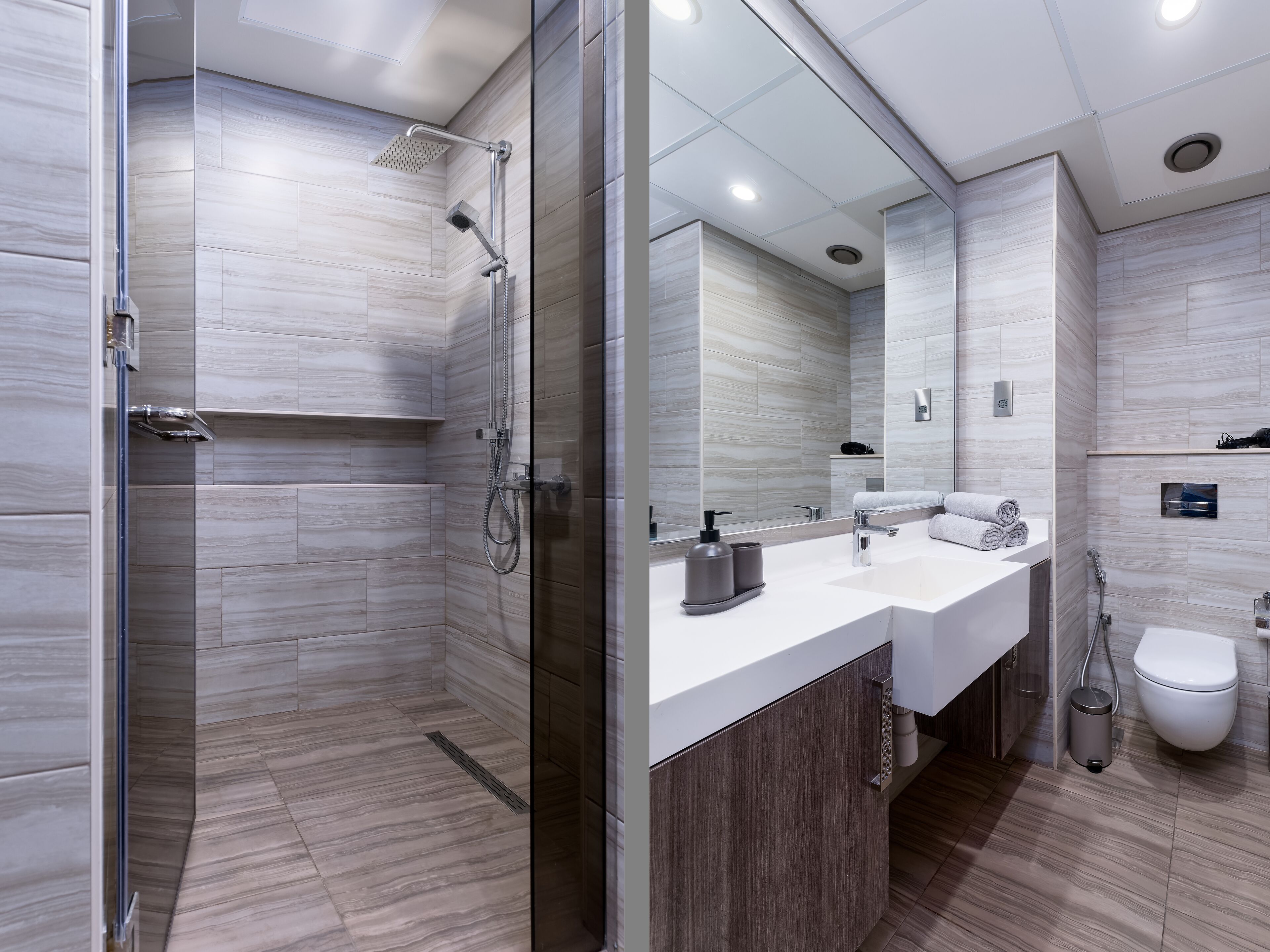A modern bathroom with a glass-enclosed shower, a vanity with a mirror, and a toilet.