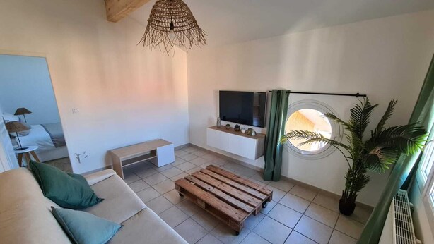 Ein modernes Wohnzimmer mit einer Couch, einem Couchtisch, einem Fernseher und einem Fenster mit Vorhängen.