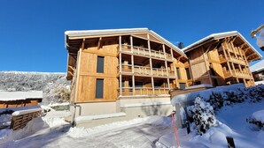 Una cabaña de madera con varios balcones y una pista de esquí al fondo.
