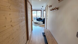 Un interior moderno con suelo de madera, un banco y un sofá al fondo.