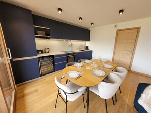 A compact kitchen with modern appliances, a dining table set for six, and a cozy seating area. - Spacious apartment with 3 en-suite bedrooms in Les Gets (Les Gets)