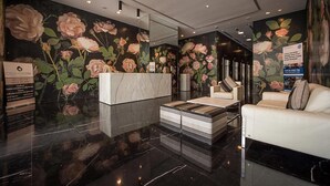 A lobby with a marble reception desk, a sofa, and a coffee table. - Beautiful 1BR with sunset view (Dubai)