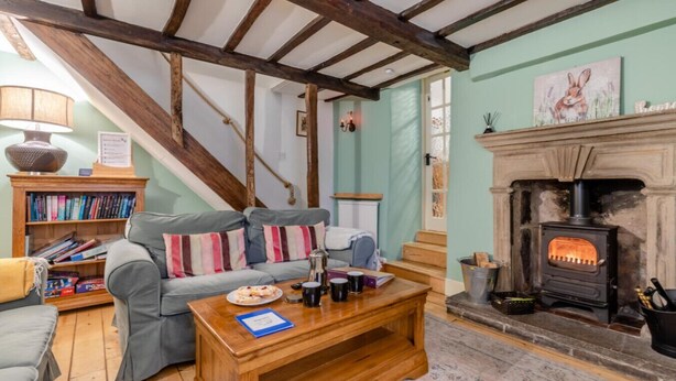 A cozy living room with a fireplace, a sofa set, a wooden coffee table, and a bookshelf.