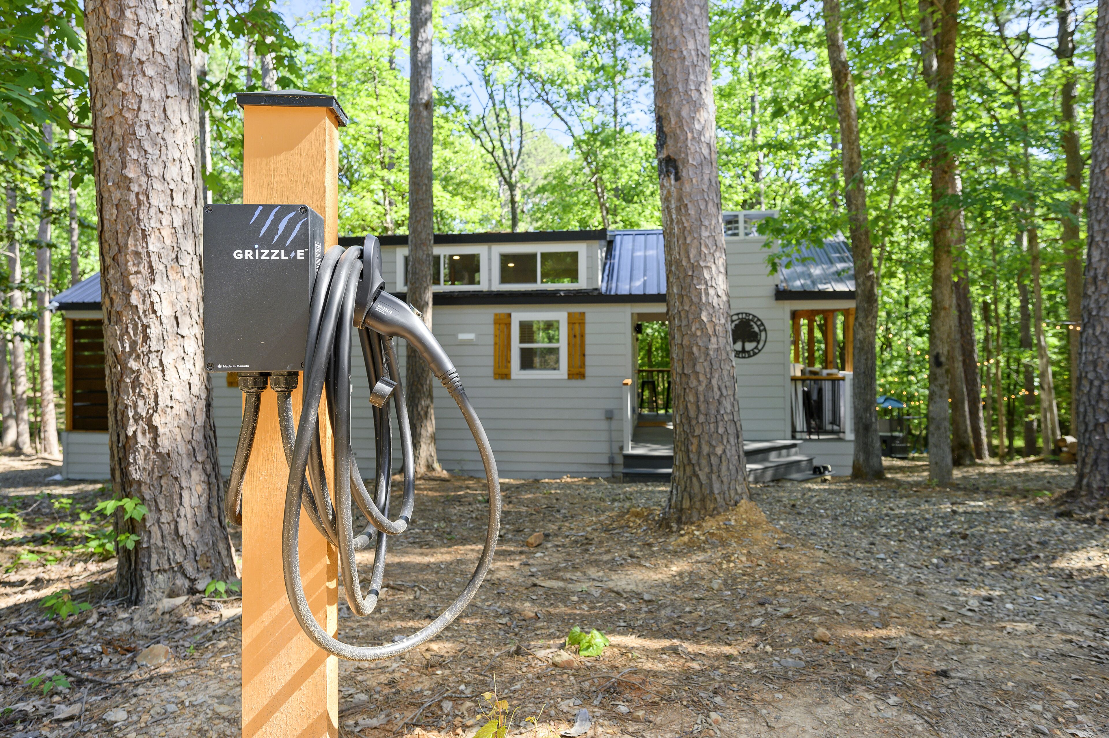 A portable RV with a solar panel charging station in a wooded area.