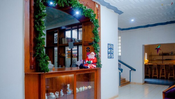A wooden cabinet with glass doors displaying ceramic figurines, a Christmas tree, and a Santa Claus figure. - LOTUS HOTEL DIEGO (Antsiranana)