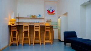 A hotel lobby with a bar area, wooden stools, a black sofa, and a sign for the Lotus Hotel. - LOTUS HOTEL DIEGO (Antsiranana)