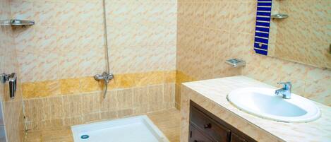 A bathroom with a bathtub, a sink, and a mirror.