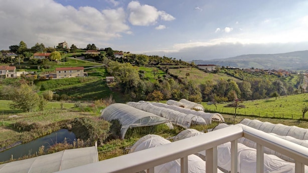 A rural landscape with green fields, a small body of water, and several buildings, including a prominent house with a red roof. - Rural lodge with garden and children's play area (Saint-Romain-en-Jarez)