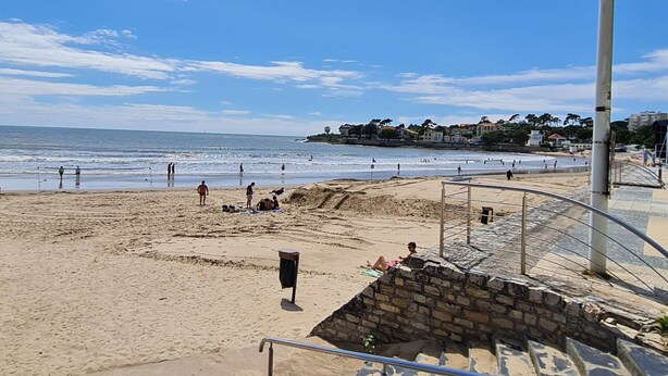 A beach with a clock on a pole, sandy beach, and a stone wall. - "Charming Studio Steps from Nauzan Beach with Private Garden and Parking" (Vaux-sur-Mer)