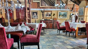Un restaurante con sillas de terciopelo rojo, mesas de madera y suelo de baldosas.