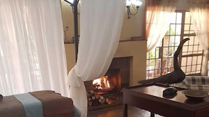 Una habitación acogedora con dos camas, una mesa con un cuenco y una chimenea.