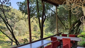 Un espacio al aire libre con mesas y sillas, rodeado de árboles y vistas a un paisaje natural.