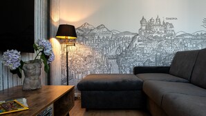 Una sala de estar moderna con un sofá, una lámpara y un mural en la pared con un paisaje urbano.