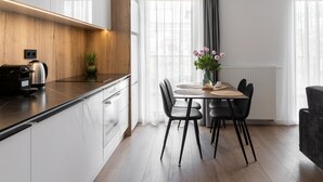 Una cocina moderna con armarios blancos, una pared decorativa de madera y un comedor con mesa y sillas.