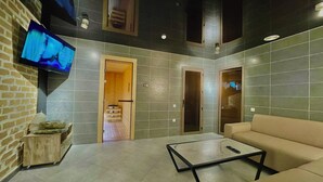 A modern living room with a sofa, a coffee table, and a TV mounted on the wall. - Alpha Plaza (Tashkent)