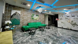 A lobby with a green sofa, marble flooring, and blue ceiling lights. - Alpha Plaza (Tashkent)